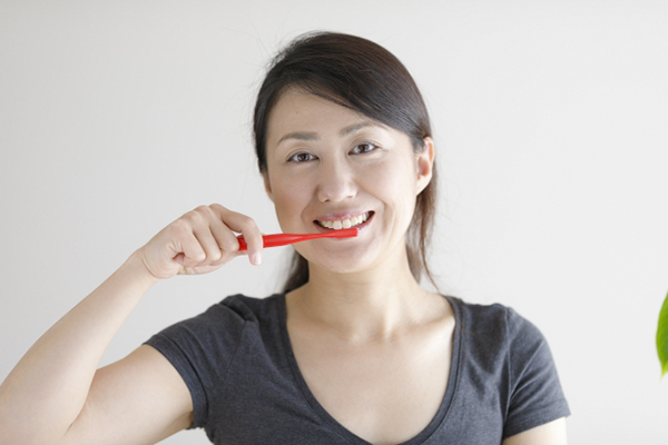 歯ブラシで歯をみがく笑顔の女性